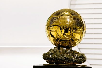 Golden football trophy silhouette surrounded by statistics and voting sheets, with the text BALLON D’OR RECORDS